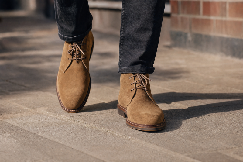 Man walking in tan suede chukka boots and dark jeans